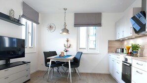 Una cocina moderna con armarios blancos, horno integrado y un comedor con mesa y sillas.