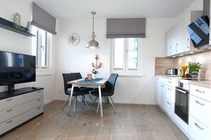 Eine moderne Küche mit weißen Schränken, einem eingebauten Ofen und einem Essbereich mit Tisch und Stühlen.