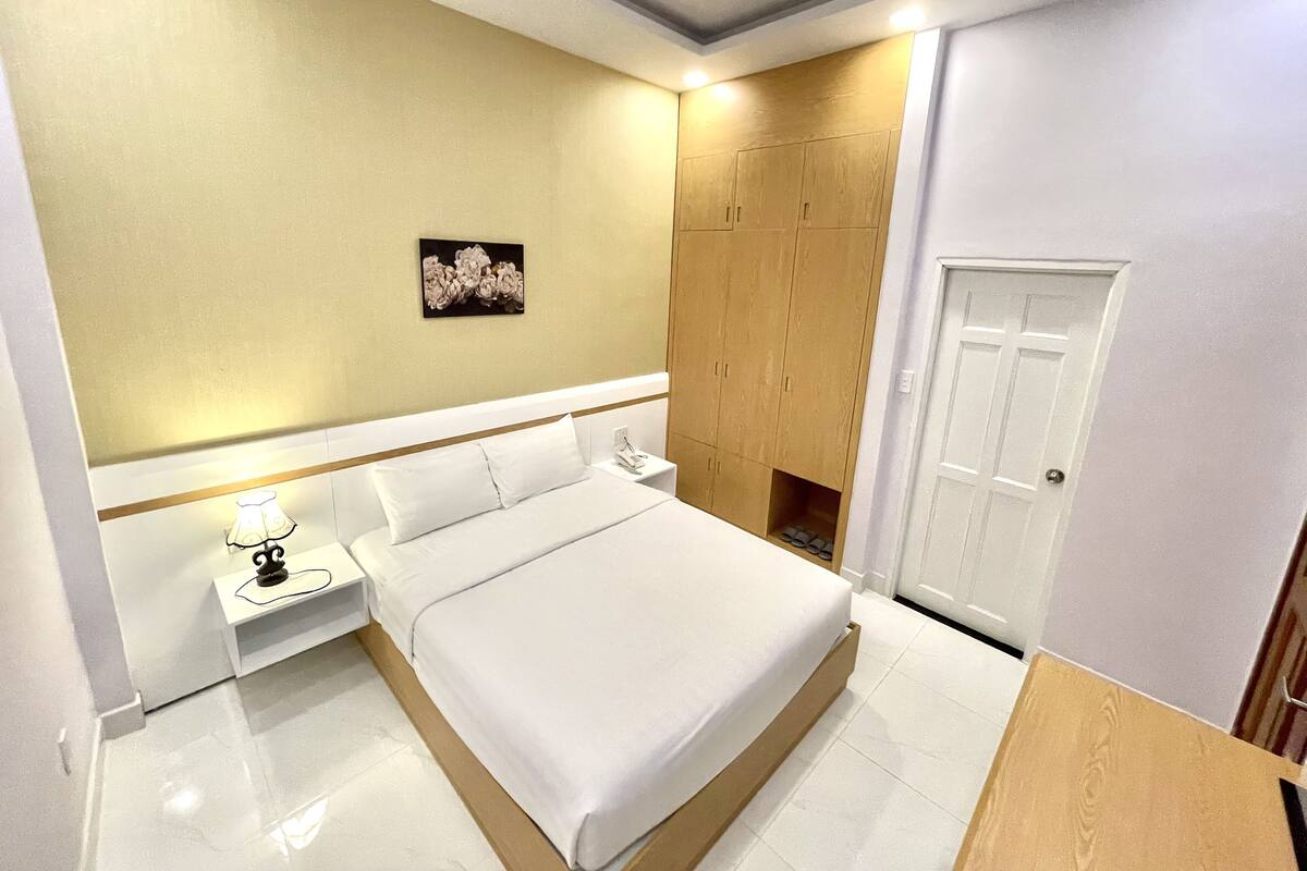 Un dormitorio moderno con una cama grande, mesitas de noche, un armario y una puerta.