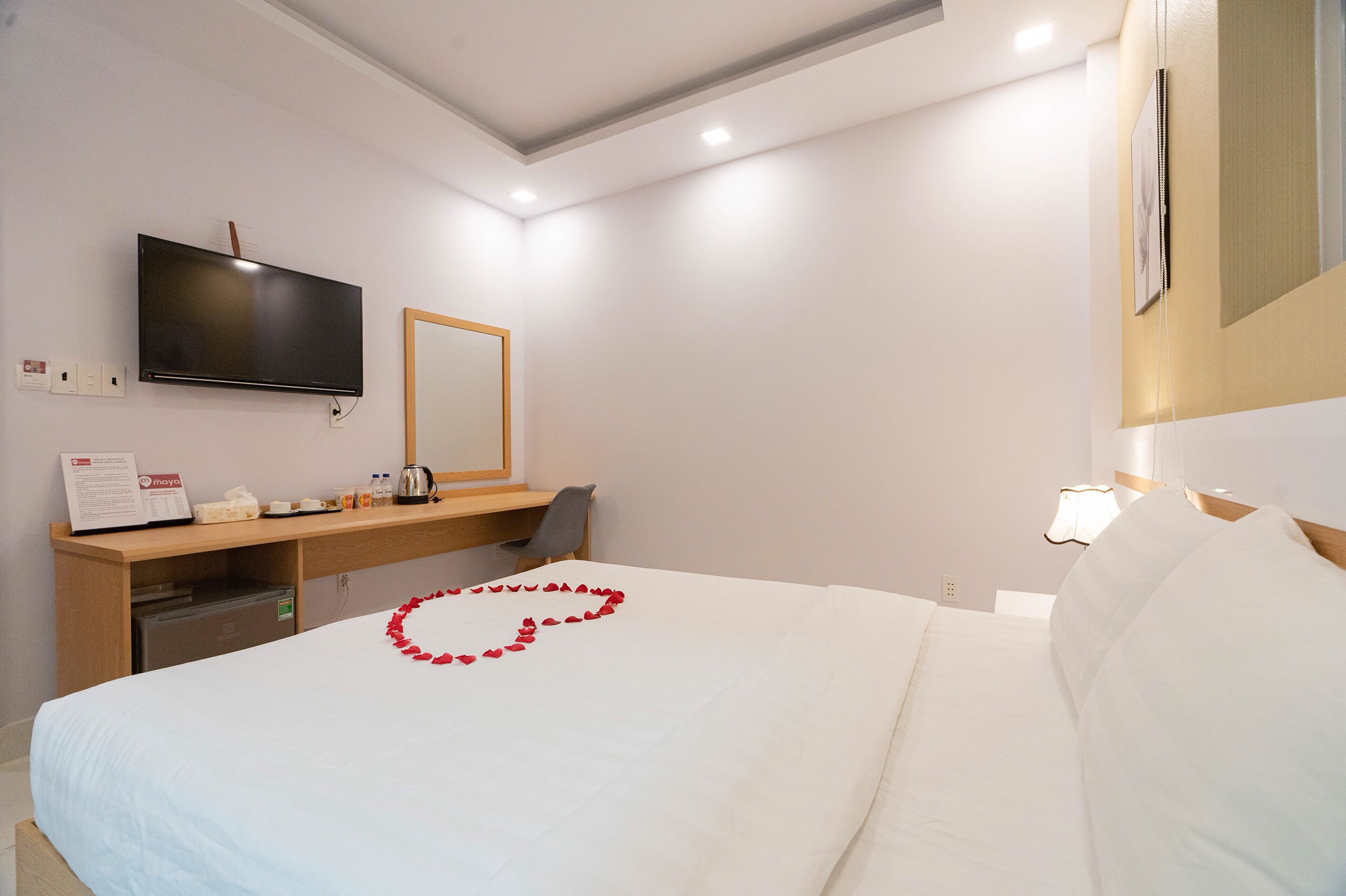 Una habitación de hotel con cama, escritorio, televisión y espejo.