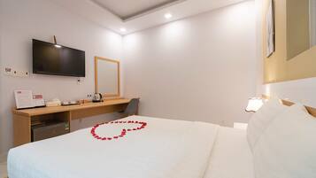 Una habitación de hotel con cama, escritorio, televisión y espejo.