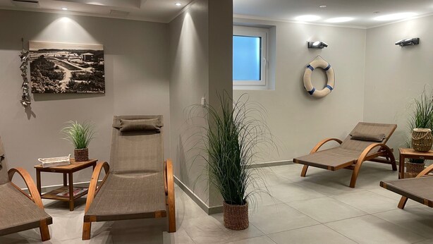 A spa room with wooden chairs, a massage table, and potted plants. - Baabe Villen Ensemble FeWo 03 Ahoi Ref. 211406 (Baabe)