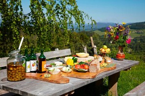 A picnic table with food, drinks, and a vase of flowers.
