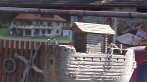 Una estructura de madera que recuerda a un castillo, con una pequeña torre, una rueda y una valla.