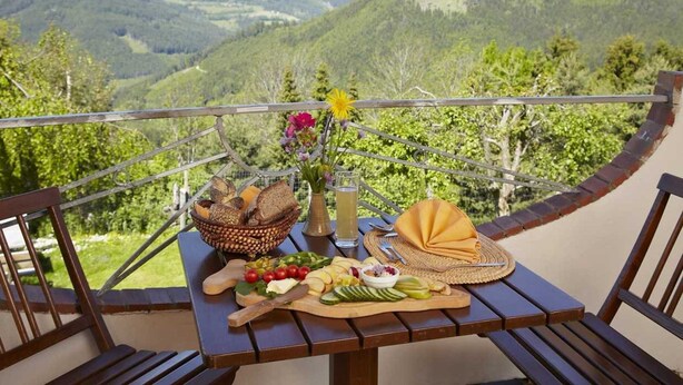 Una mesa con diversos alimentos y vista a un paisaje montañoso.