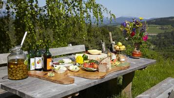 A picnic table with food, drinks, and a vase of flowers.
