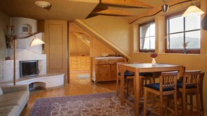 Ein gemütliches Zimmer mit Kamin, Holztisch und Stühlen.