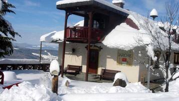 Um edifício coberto de neve com uma varanda e um letreiro que diz 'ARCHE'.