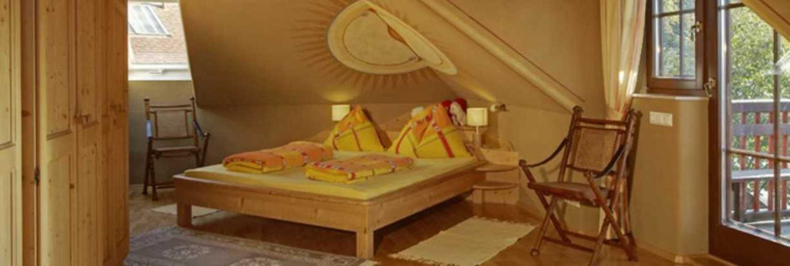 Een kamer met een bed, een stoel, een raam en een deur.