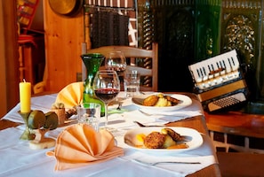 A dining table with plates of food, wine glasses, and a candle.