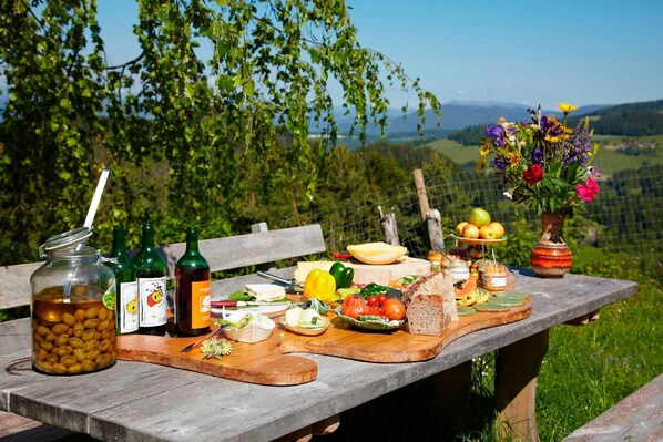 A picnic table with food, drinks, and a view of the countryside.