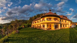 Suuri, monikerroksinen rakennus, jonka katto on kaareva. Sen ympärillä on hyvin hoidettu nurmikko ja puita.