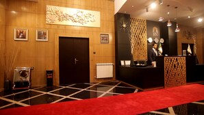 Un hall d'hôtel avec un tapis rouge, des boiseries et un comptoir d'accueil.