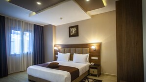 Une chambre d’hôtel avec un grand lit, une table de chevet, une lampe fixée au mur et un tableau.