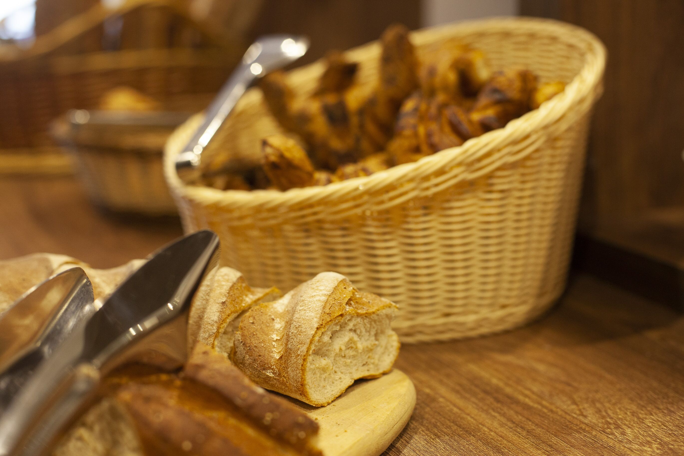 A basket of dried fruits and a loaf of bread on a wooden surface.