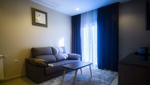 Un salon moderne avec un canapé, une table basse, un tapis et un tableau accroché au mur.