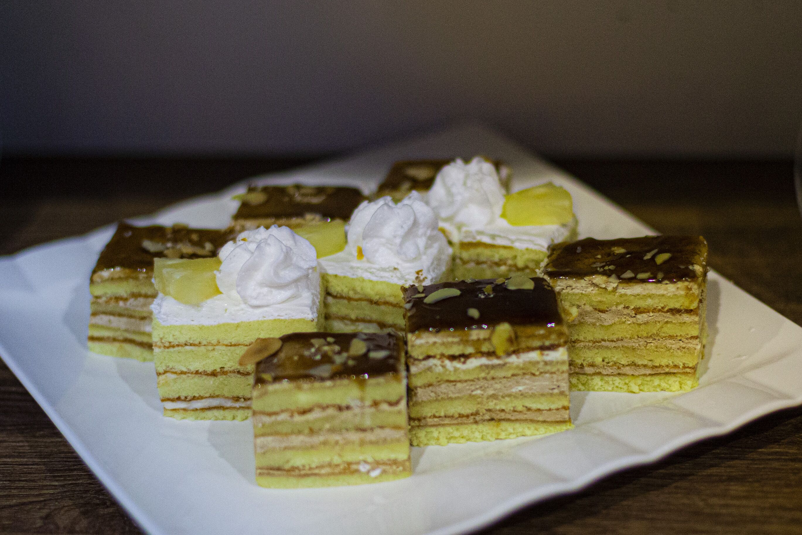 A plate of layered cakes with whipped cream and nuts.