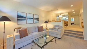 A living room with a sofa, armchairs, a glass coffee table, and a dining area in the background. - McCloud Condo | Community Hot Tub | Deck | BBQ (Incline Village)