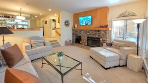 A living room with a fireplace, a television, and a staircase leading to another level. - McCloud Condo | Community Hot Tub | Deck | BBQ (Incline Village)