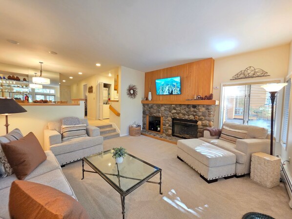 A living room with a fireplace, a television, and a staircase leading to another level.