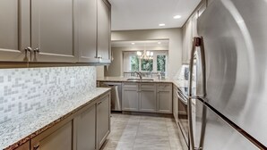 A modern kitchen with stainless steel appliances, a tiled backsplash, and a view of the outdoors. - Pet Friendly | Luxury Beachwood Townhome | Directly Across the Street from the Beach (Fernandina Beach)