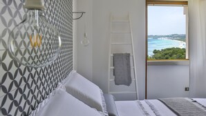 A bedroom with a bed, a ladder, a window with a view of the sea, and a patterned wall. - Apulia Suite★Rooftop Terrace&Direct Beach Access★by Amarena Collection Gallipoli (Gallipoli)