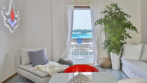 A modern living room with a sofa, a dining table, and a view of the sea through a large window. - Apulia Suite★Rooftop Terrace&Direct Beach Access★by Amarena Collection Gallipoli (Gallipoli)