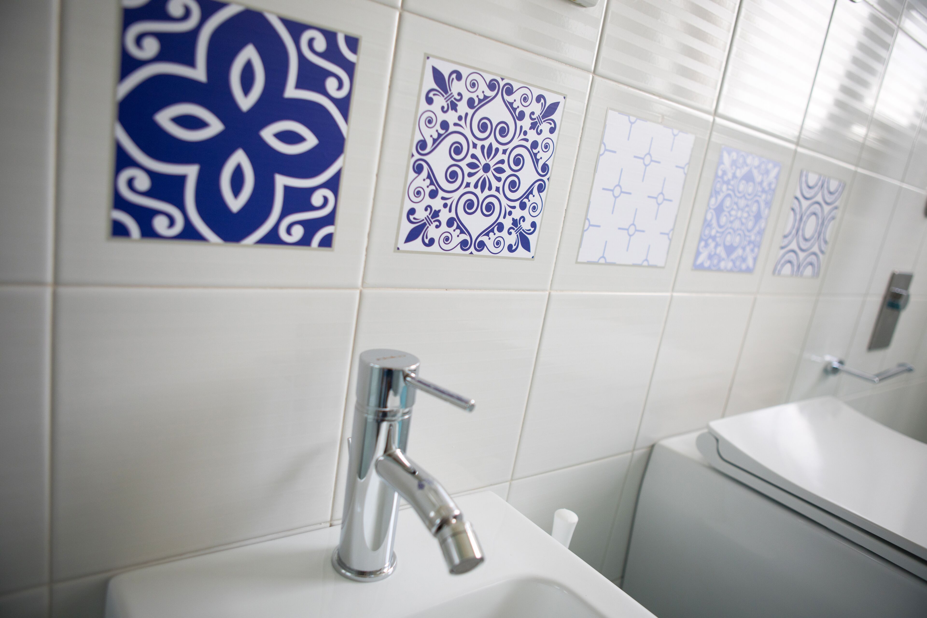 Un baño con un lavamanos moderno, un grifo cromado y azulejos decorativos en la pared.