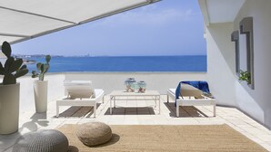 A sunlit patio with white furniture, a table with decorative items, and a view of the sea. - Apulia Suite★Rooftop Terrace&Direct Beach Access★by Amarena Collection Gallipoli (Gallipoli)