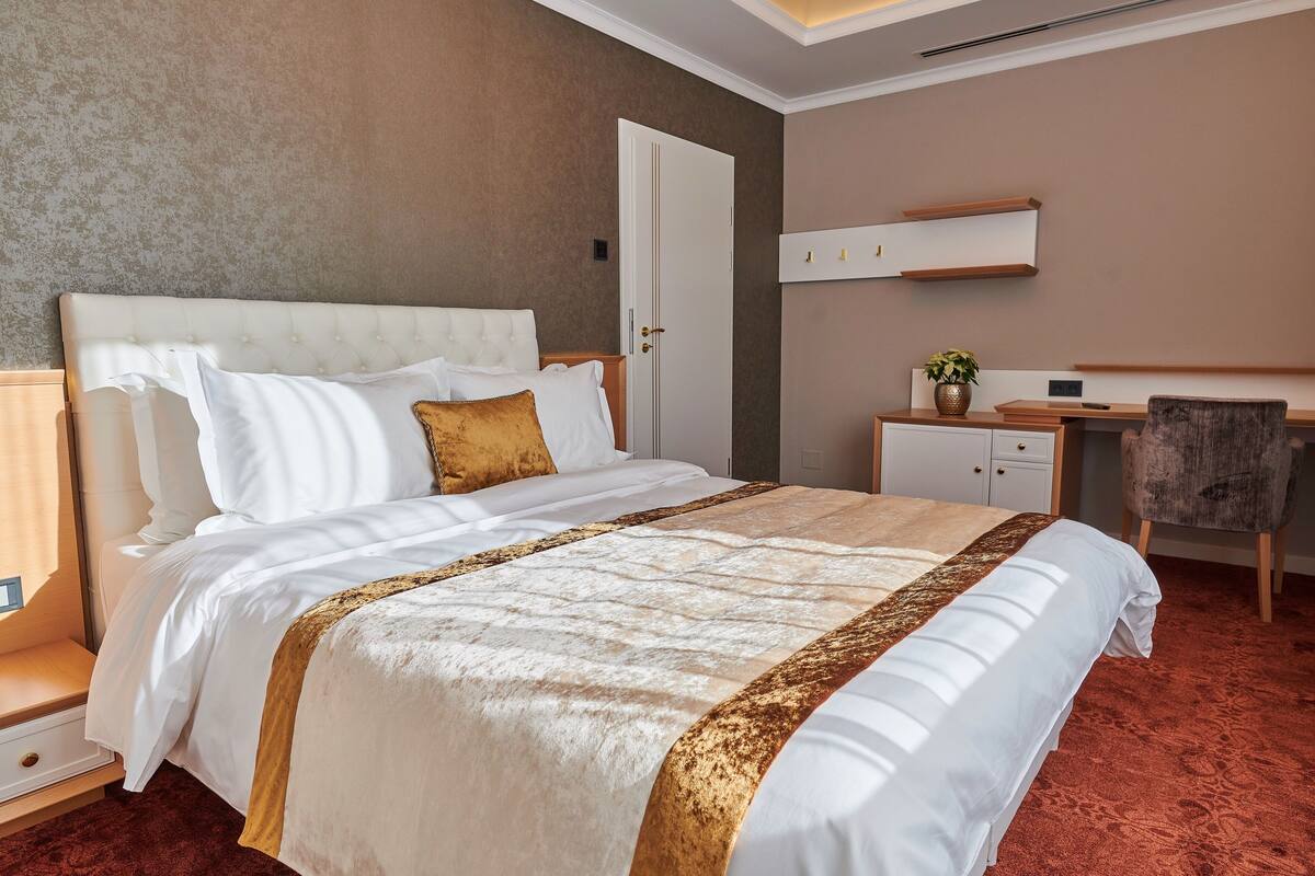 Una camera d'albergo con un letto grande, una scrivania, una sedia e un armadio.