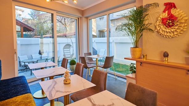 Un moderno comedor interior con ventanas amplias, una araña y un adorno circular en la pared.