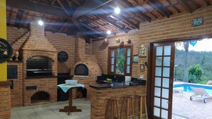 A kitchen with a brick oven, a bar area, and a view of a pool. - Holiday Home in Atibaia  (Atibaia)