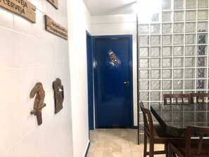 Guest room with a blue door, tiled walls and floor, and a glass partition with a grid pattern.