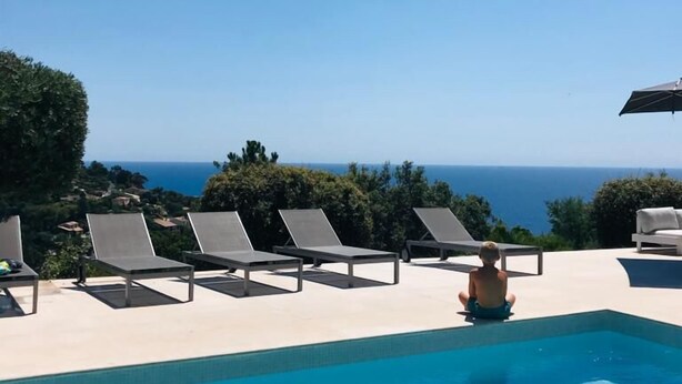 Un espace piscine avec des chaises longues et vue sur l’océan.