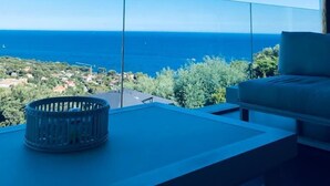 Un balcon moderne offrant une vue dégagée sur l’océan et une ville située au loin.