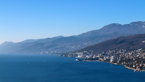 A coastal city with a view of the sea and mountains in the background.
