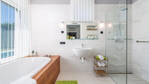 A modern bathroom with a freestanding bathtub, a large sink, and a glass-enclosed shower.