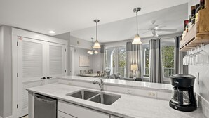 Una cocina moderna con una isla grande, electrodomésticos de acero inoxidable y una cafetera.