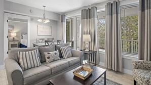Una sala de estar moderna con un sofá gris, una mesa de centro y un comedor al fondo.