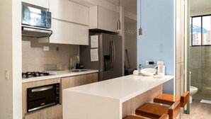 Eine moderne Küche mit Kochinsel, Einbauofen, Edelstahl-Kühlschrank und Mikrowelle.