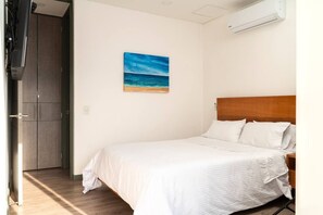 A bedroom with a bed, a painting of a beach, and an air conditioning unit on the wall. - Charming and Luxury Suite with Panoramic View-2 AC (Medellín)