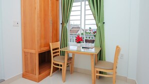 Une pièce comprenant un meuble en bois, deux chaises, une table et une fenêtre ornée de rideaux verts.