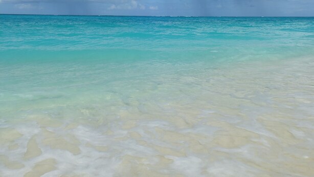 Een strand met helder turquoise water en een zandstrand.