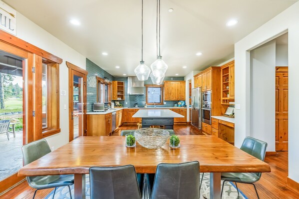 A modern kitchen with wooden cabinets, a large island, and a dining area with a wooden table and chairs.