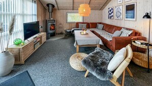 Ett mysigt vardagsrum med en öppen spis, en soffa, en tv och en matplats.