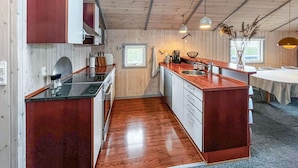 Ett kompakt kök med träskåp, en köksö och en matplats med ett bord.