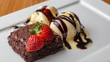 A dessert plate with a brownie, ice cream, and chocolate sauce.