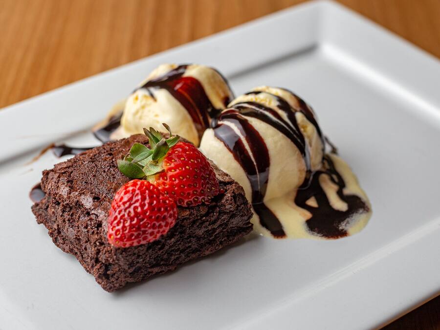A dessert plate with a brownie, ice cream, and chocolate sauce.