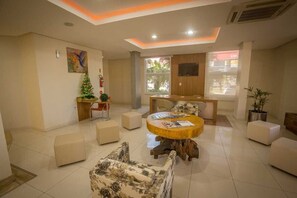 Un comedor moderno con una mesa redonda de madera, asientos acolchados y un árbol navideño decorativo.