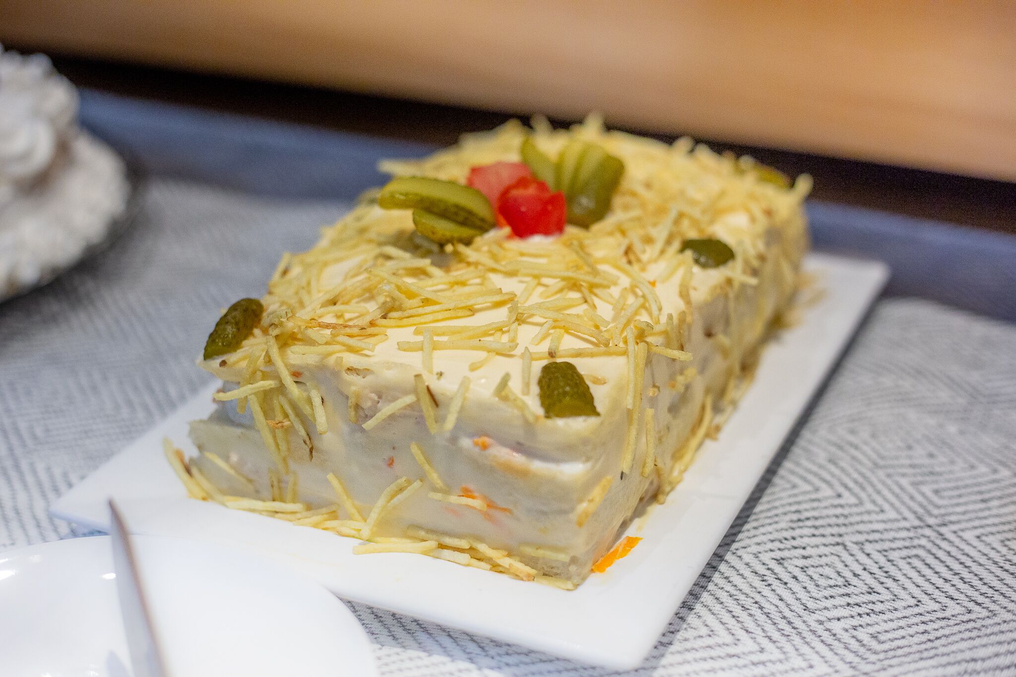 Un plat rectangulaire garni d’une préparation émiettée et de quelques décorations, le tout présenté sur une assiette blanche.